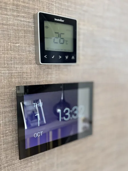 Touch screen showing the time and date, with a Heatmiser thermostat set to 26 degrees fixed just above it