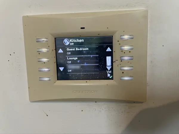 Earlier Crestron colour touch panel with a list of rooms that includes the kitchen, a guest bedroom and the lounge
