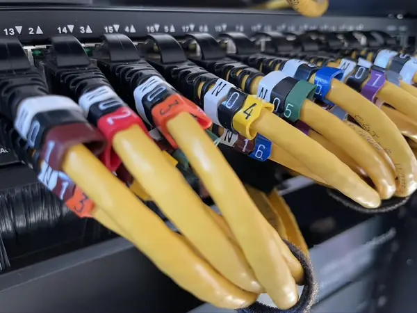 Row of yellow patch leads plugged into the PoE switch, every one carrying a numbered, colour coded tag