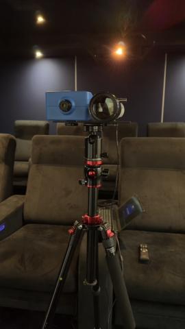 A calibration meter on a tripod among the seats of a home cinema room