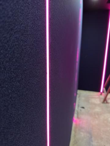 Close up of a cinema fabric wall panel with a pink LED strip running down the join
