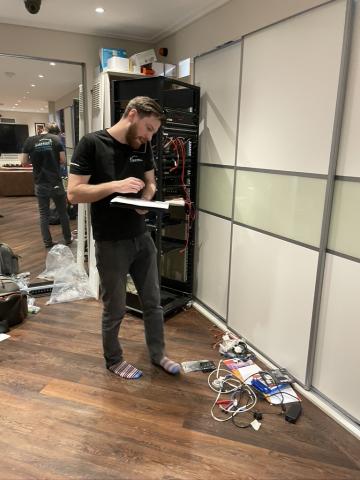 An engineer making notes beside the equipment rack while documenting the system