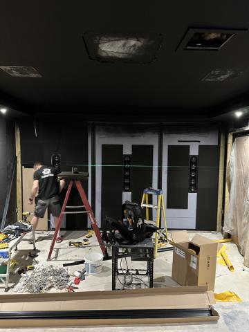 A home cinema room during installation, with the front wall being built and a laser level line across the room