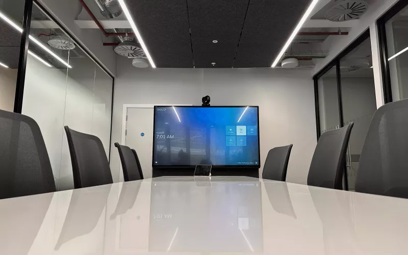 London meeting room with a display, a camera above it and a touch panel on the table