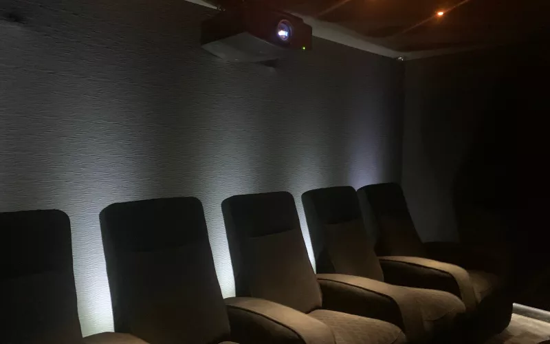 Home cinema lighting in Berkshire: recliners in front of a textured wall washed with white light, and a projector high on the back wall