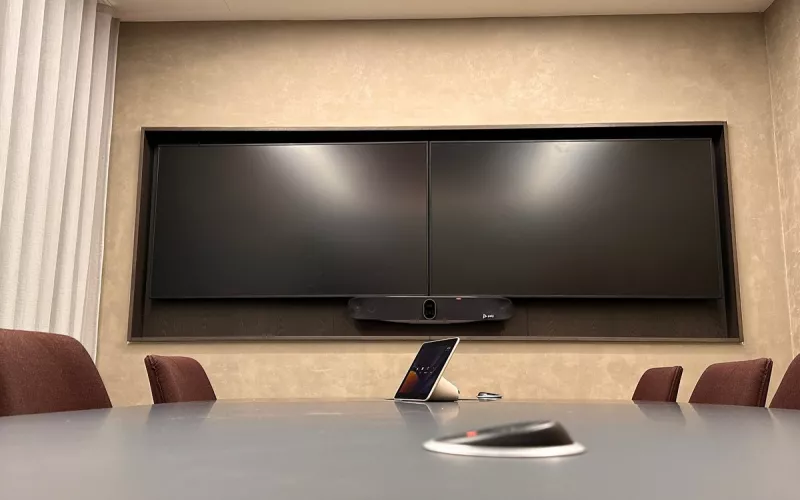 Meeting room AV installation in London: twin displays side by side above a Poly video bar, with a touch controller on the table