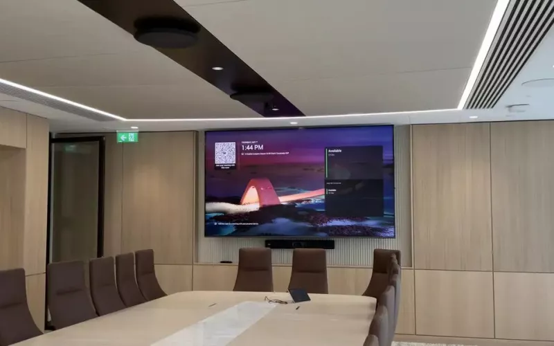 Timber panelled boardroom with a long table, leather chairs, a wall display with a video bar beneath it and ceiling microphones, the size of room a Biamp Devio UCX system with ceiling microphones is designed for
