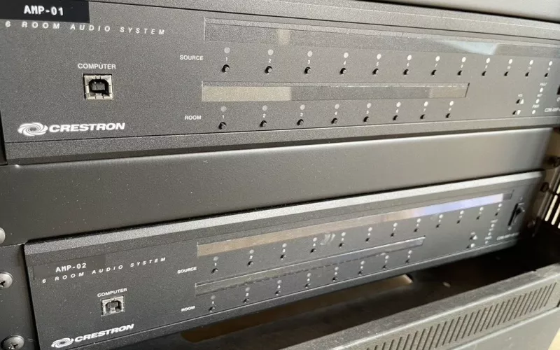 Kept through the Crestron upgrade: the AMP-01 and AMP-02 audio units, each feeding six rooms, in their place in the rack