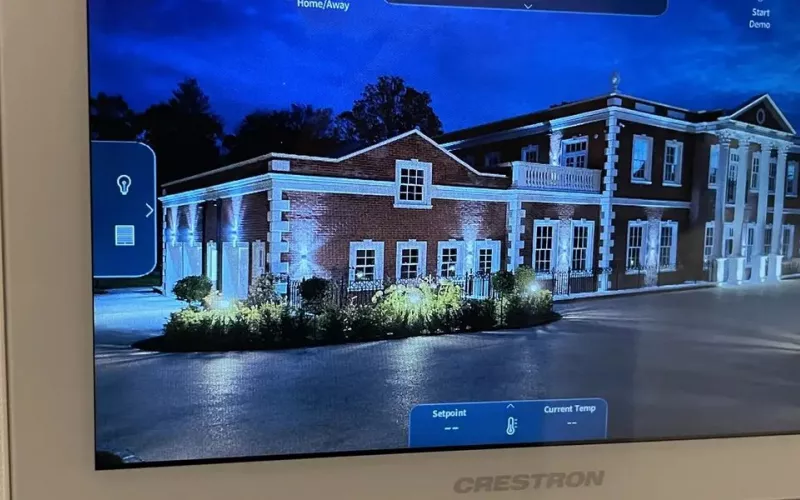 Crestron touch screen on a wall showing controls for lighting, blinds, heating and music