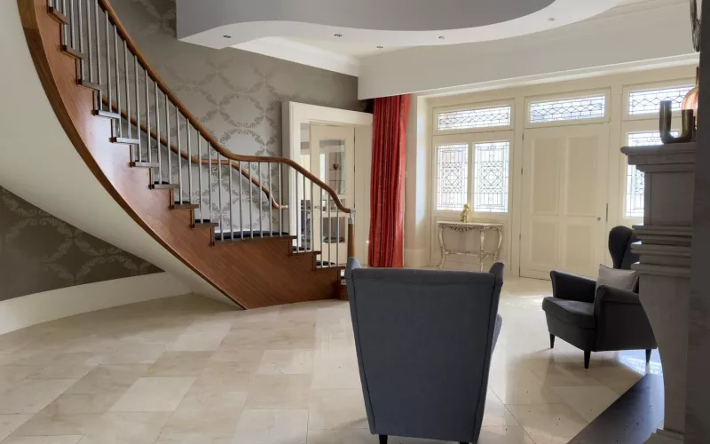 Staircase curving up in timber from a polished marble floor, two armchairs against the wall: the entrance hall of a house with Control4 network problems
