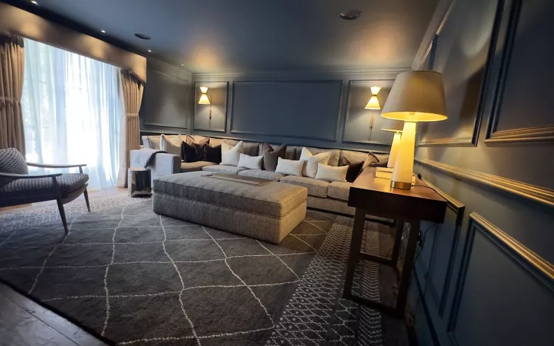 Finished living room in the Winchester townhouse, with dark panelled walls, wall lights and a long corner sofa, a renovation we worked on with an architect in Hampshire