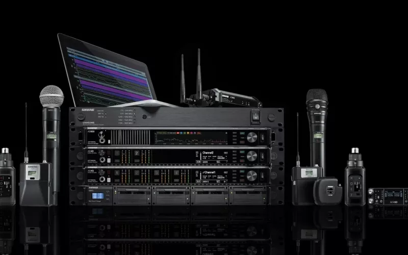 Shure Axient Digital system on a black background: AD4D and AD4Q receivers, AD600 and UA845UWB in a rack with an AD610 access point on top, a laptop, and handheld and bodypack transmitters either side