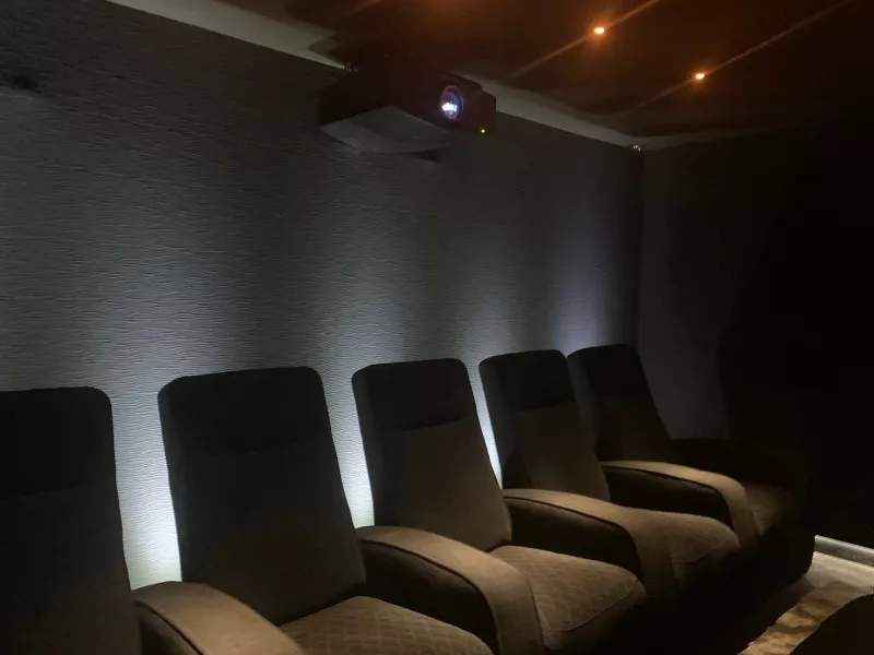 Home cinema lighting in Berkshire: recliners in front of a textured wall washed with white light, and a projector high on the back wall
