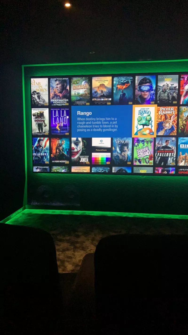 Home cinema screen framed by a green LED surround, with a second strip of green light along the floor line beneath it