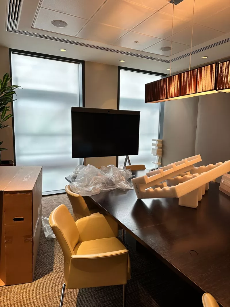 Unpacking day: cardboard and foam from the delivery lie on the table while the screen waits upright on its stand
