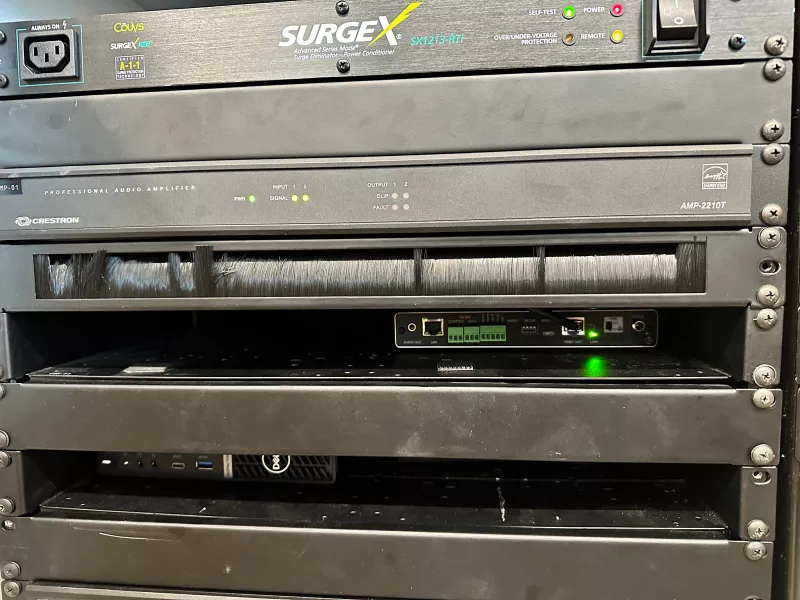 The front of the equipment rack, from the SurgeX unit at the top through the Crestron amplifier and a brush strip down to the Dell mini PC, which has a shelf to itself