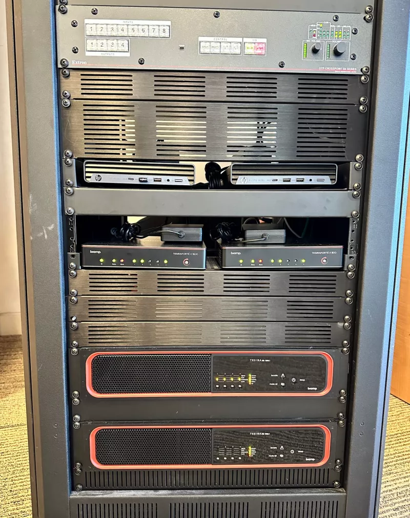 Reading down the lower rack: switching from Extron, two compact HP computers, the Biamp TesiraFORTÉ X processors and, at the base, two Biamp amplifiers with red trim