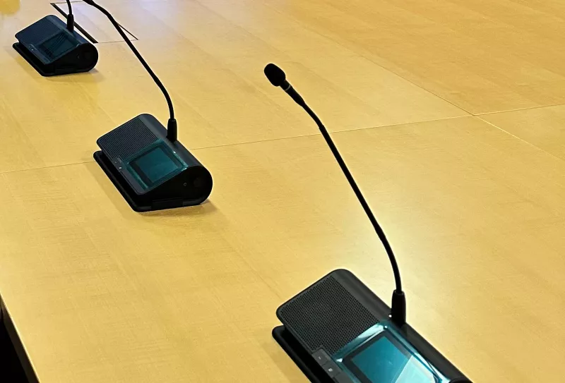 Three of the microphone units up close, each with a slim gooseneck, a small display with buttons and a speaker grille