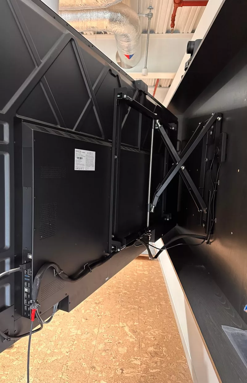 Back of an Avocor display pulled out from the wall on a swing arm, with cables gathered in braided sleeving