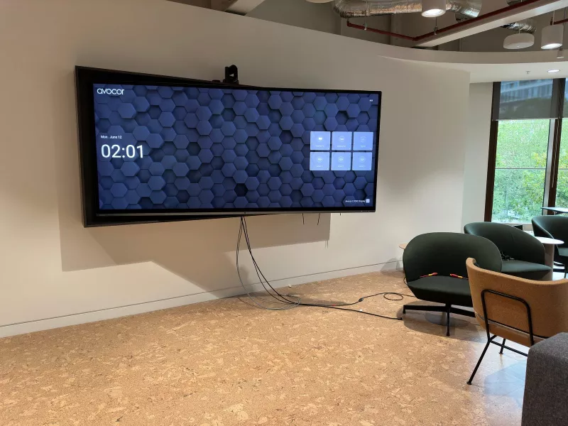 Avocor L Series ultra wide display on a lounge wall in London with a camera on top and its input menu on screen