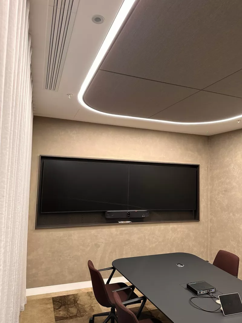 Meeting room with a curved line of light around a fabric ceiling panel, sheer curtains and twin displays above a video bar