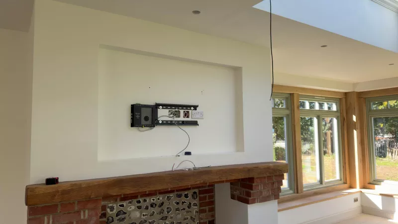 Recess above a fireplace in a Hampshire new build with a flat black bracket, back boxes, a double socket and a Crestron box before the TV is fitted