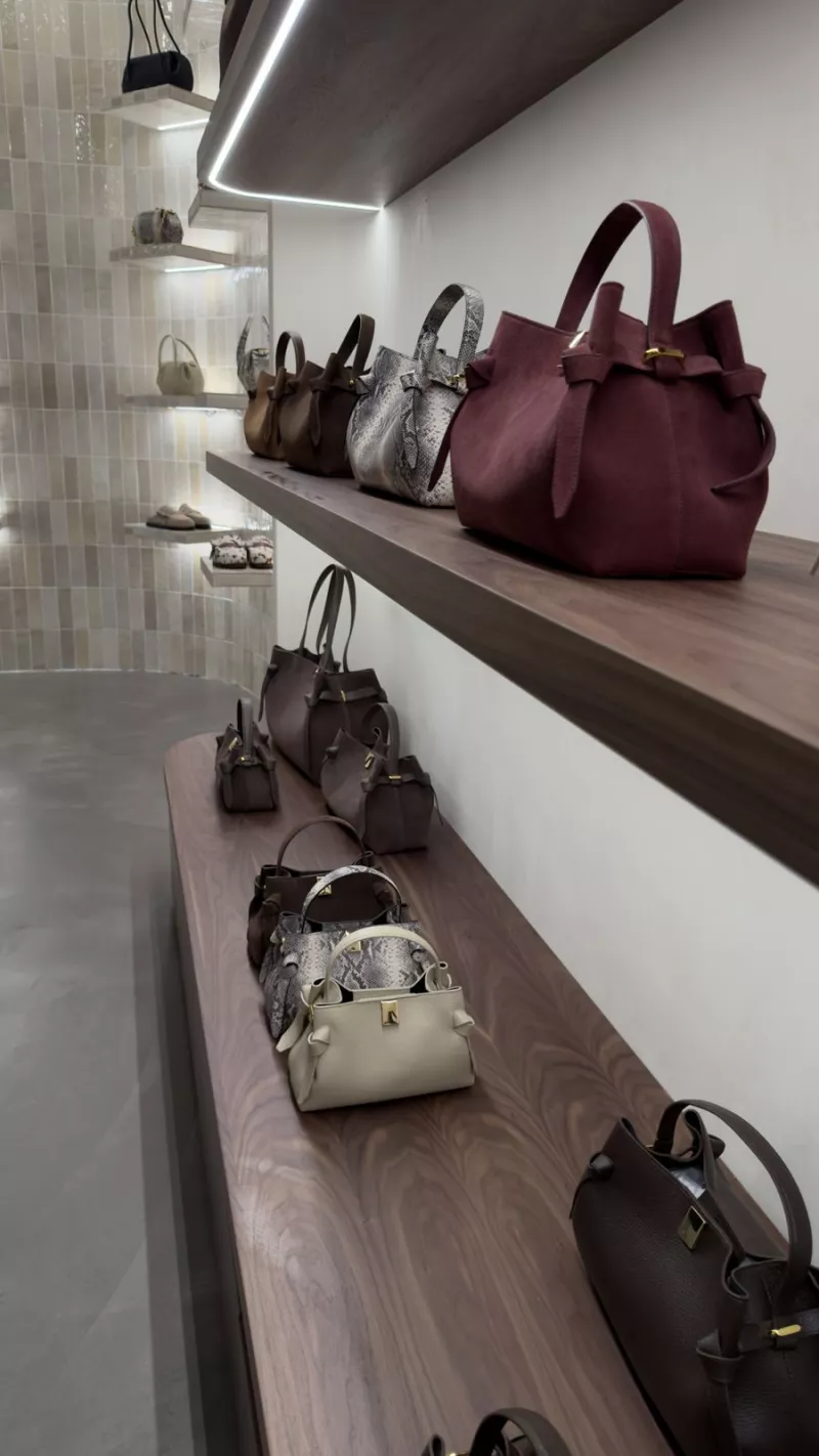 Handbags on lit walnut shelving in the Yuzefi flagship