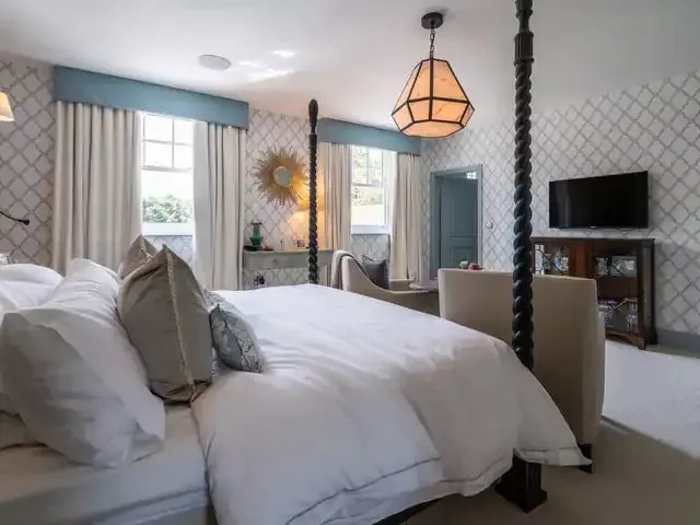 Four poster bedroom with floor length curtains, a wall mounted TV and a lantern pendant, the kind of room a KNX installer in London links to one keypad