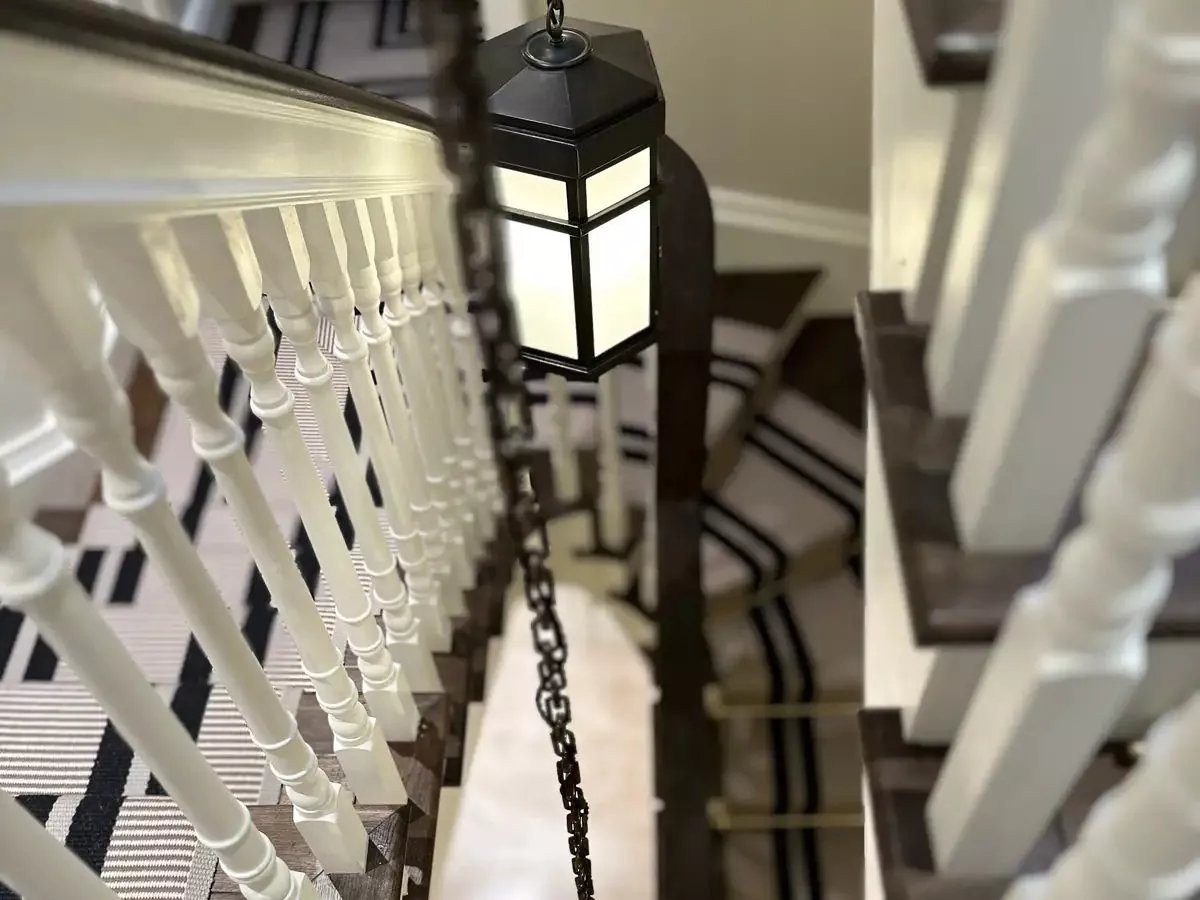 Lantern pendants hanging beside white spindles on a stair, lighting that a KNX installer in Hampshire can dim from any floor