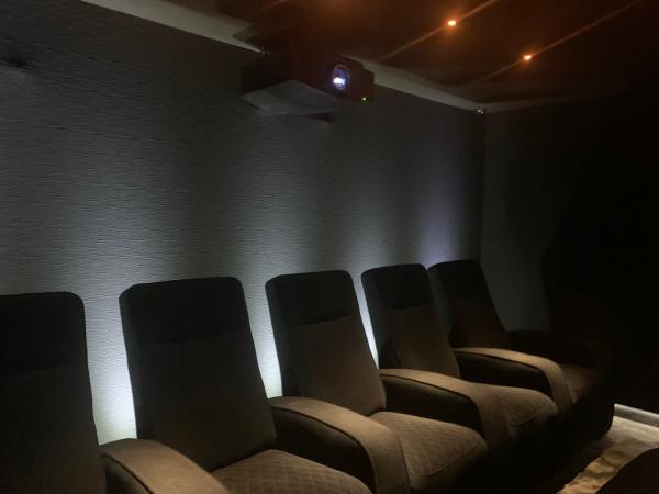 Home cinema lighting in Berkshire: recliners in front of a textured wall washed with white light, and a projector high on the back wall