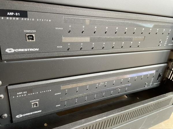 Kept through the Crestron upgrade: the AMP-01 and AMP-02 audio units, each feeding six rooms, in their place in the rack