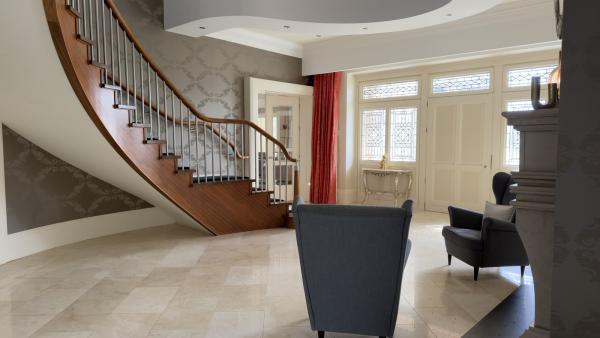Staircase curving up in timber from a polished marble floor, two armchairs against the wall: the entrance hall of a house with Control4 network problems