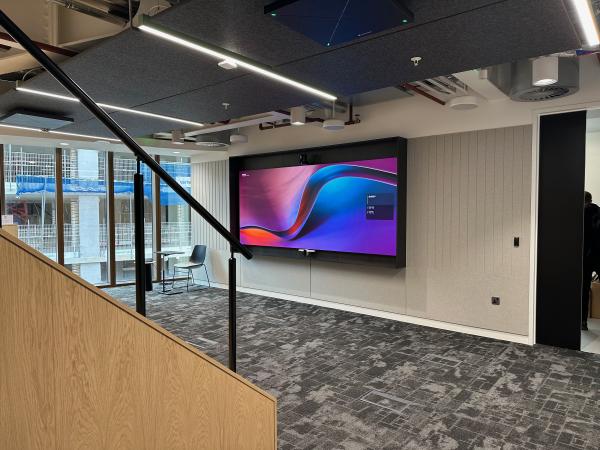 Large display with a camera and video bar on a panelled wall in a London office