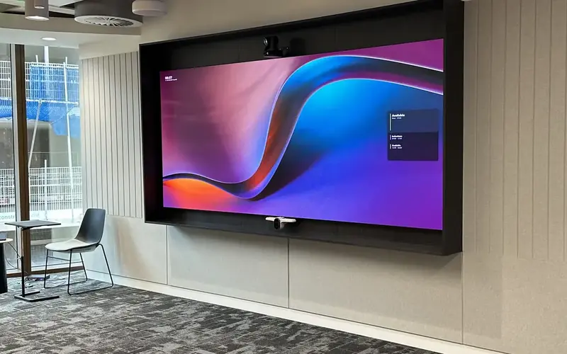 Large wall mounted display in an open plan office showing a colourful graphic