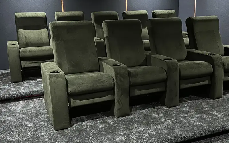 Rows of green velvet recliners in a dedicated home cinema