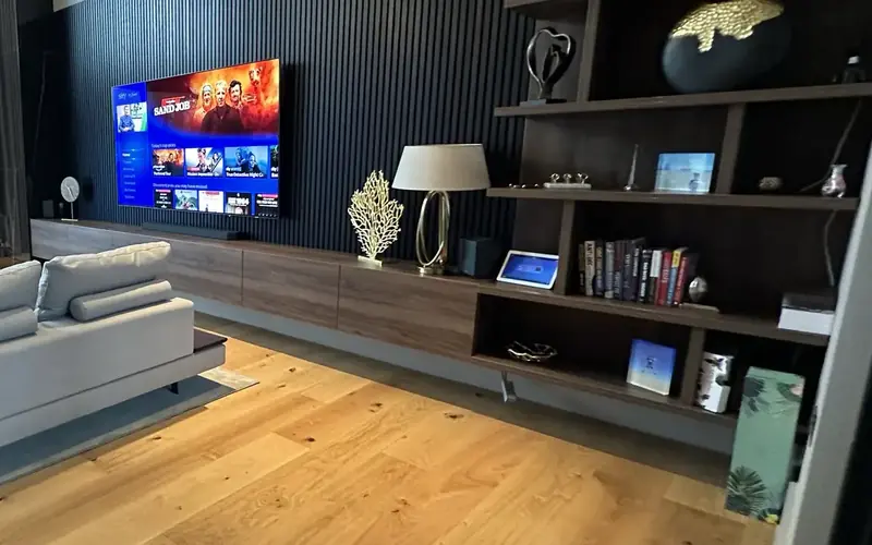 Living room with a wall mounted TV and shelving, with integrated audio