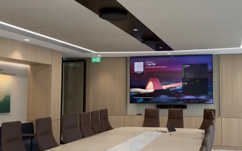 Boardroom with a large wall display, a long table and brown leather chairs