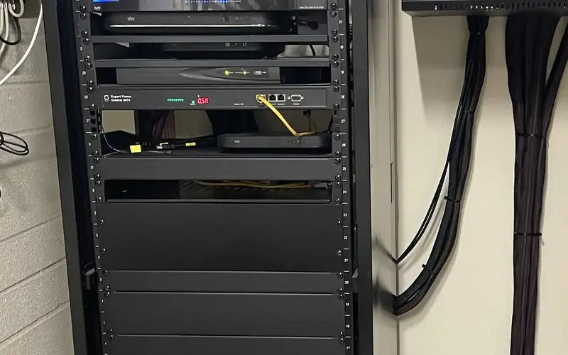 Equipment rack with black cables bundled neatly down the wall beside it
